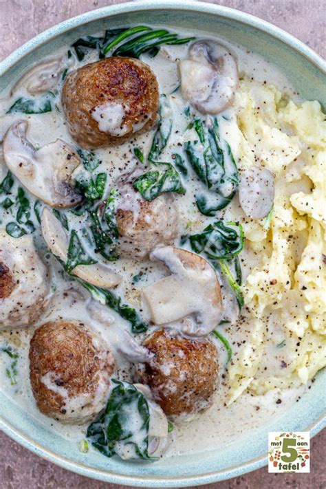 A Bowl Filled With Pasta And Meatballs Covered In Gravy On Top Of A Table