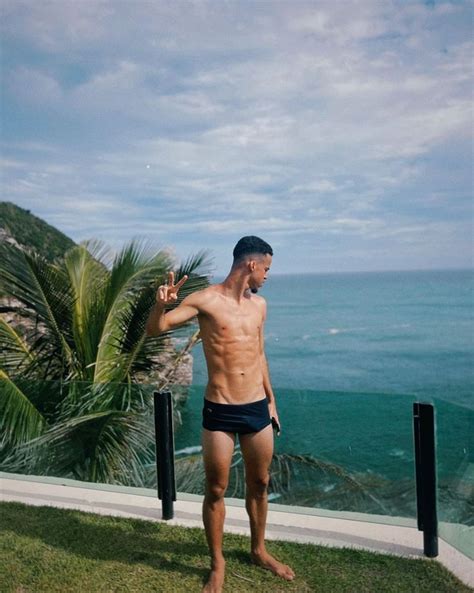 A Man Standing On Top Of A Lush Green Field Next To The Ocean