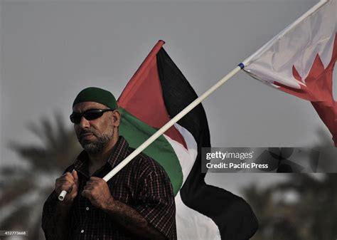 A Bahraini Man Carries His Country Flag And The Flag Of Palestine In