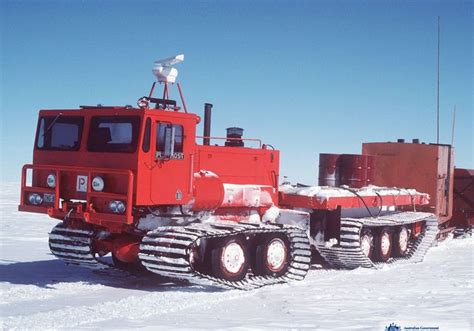 a red truck is parked in the snow with two other trucks behind it and ...