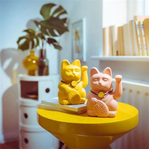 two small plastic cats sitting on top of a yellow table