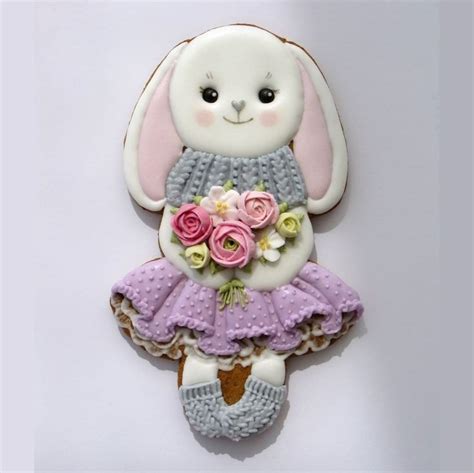 A Cookie Shaped Like A Bunny With Flowers In Her Skirt And Booties On It