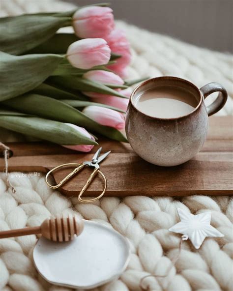 A Cup Of Coffee Next To Some Flowers And Scissors On A Table With Other