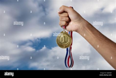 Mano Sujetando Medalla De Oro Contra Fondo Nublado Cielo En La Mano