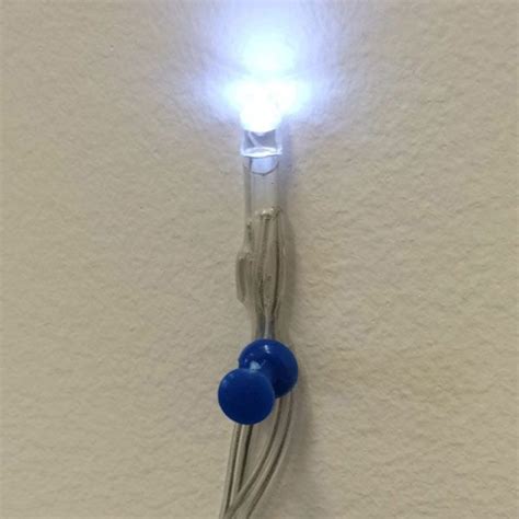 A Light That Is On The Side Of A Wall With Two Blue Balls Attached To It