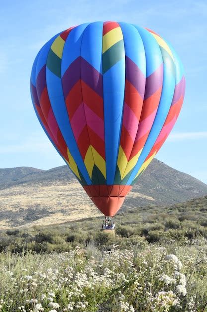 Premium Photo Hot Air Balloon Flying Over Mountain Against Sky