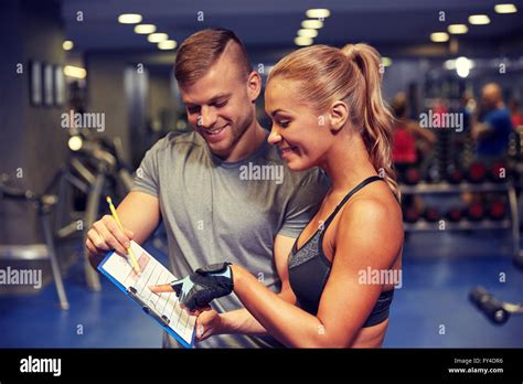 Smiling Woman With Trainer And Clipboard In Gym Stock Photo Alamy