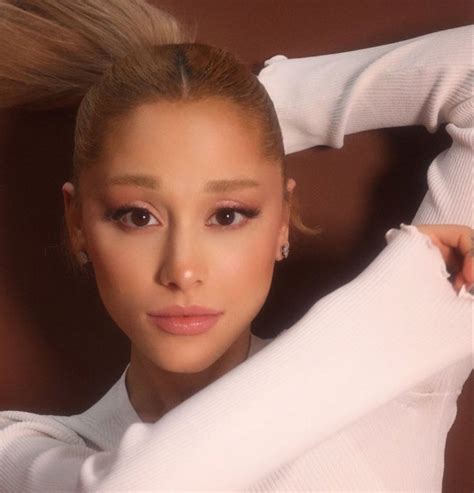 A Woman With Blonde Hair Wearing A White Sweater And Posing For A Photo