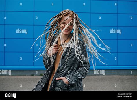 Shaking Dreads Lighthearted Teenage Girl In Front Of A Blue Panel Wall Covering She Is Wearing