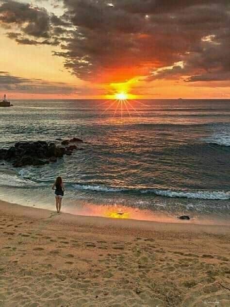 A Person Standing On The Beach Watching The Sun Go Down Over The Ocean