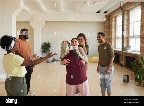 Group of young happy people greeting each other embracing and talking while standing in dance ...