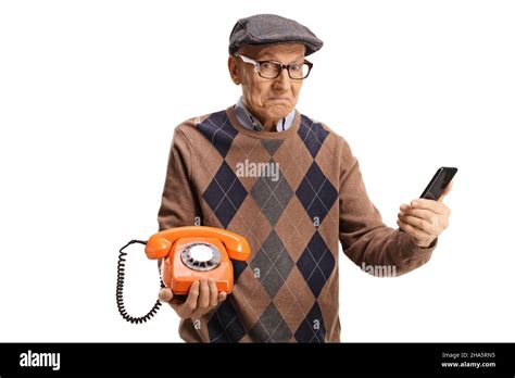 Confused Elderly Man Holding A Vintage Rotary Phone And A Smartphone