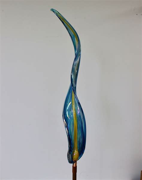 a blue and yellow glass sculpture sitting on top of a wooden stand