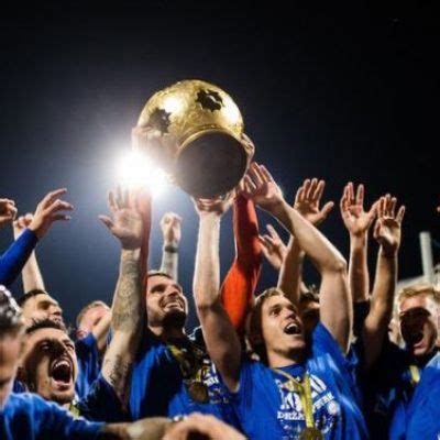 A Group Of People Holding Up A Trophy In Front Of Their Faces And Hands