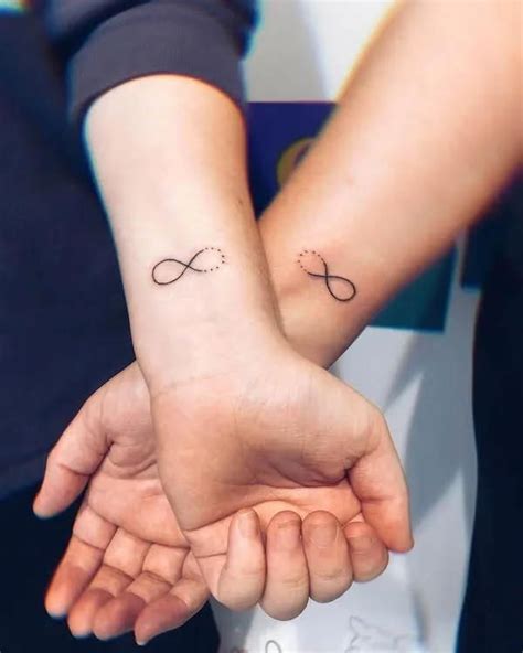 Two People Holding Hands With Small Tattoos On Their Wrist And One Has