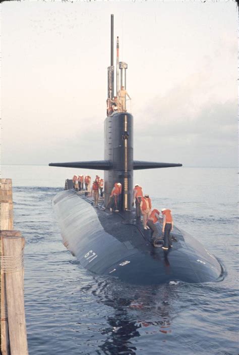 A Submarine Is In The Water With People Standing On It S Side And Looking Around