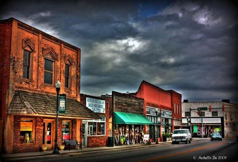 an old western town with cars parked on the street and storm clouds in ...