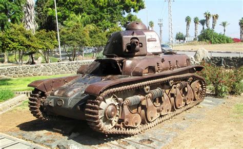 An Old Rusted Tank Sitting On Top Of A Brick Walkway Next To A Park