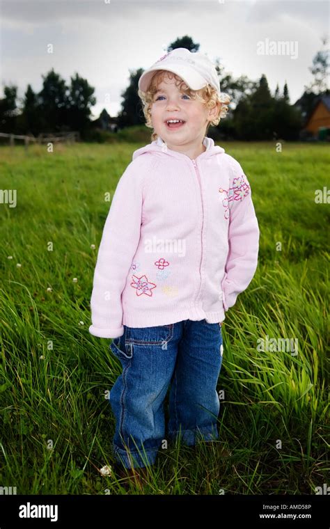 Very young girl standing in a meadow Stock Photo - Alamy