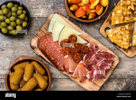 Traditional spanish tapas. Croquettes, olives, omelette, ham and patatas bravas on wooden table ...