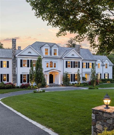 A Large White House Sitting On Top Of A Lush Green Field