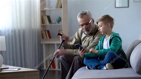 Chico explicando al abuelo cómo usar el teléfono celular tecnologías