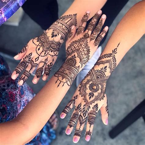 Two Girls With Henna Tattoos On Their Hands Are Holding Onto Each Other