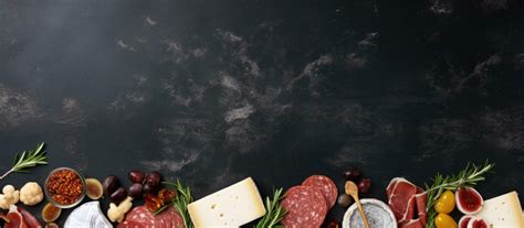 Photo of an assortment of meats and cheeses on a black background with