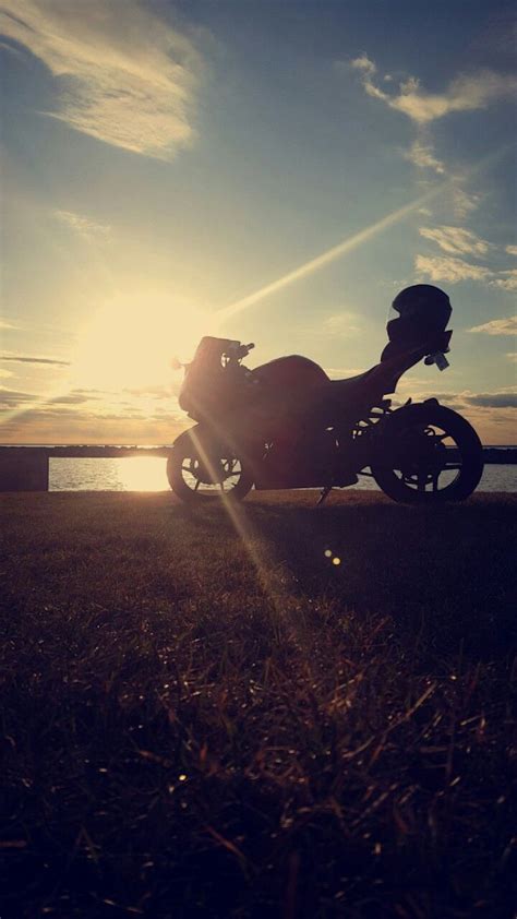 A Motorcycle Parked On The Side Of A Road Next To Some Grass And Water