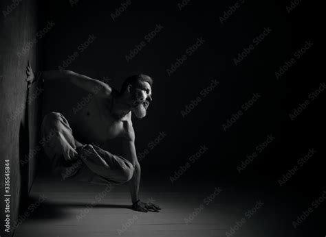 Aged Man Naked Torso In Brown Pants Is Practicing Yoga Legs In Lotus Pose Setting One Hand