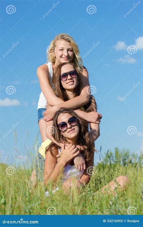 Tres Muchachas Bonitas Felices Que Abrazan Contra El Cielo Azul Imagen