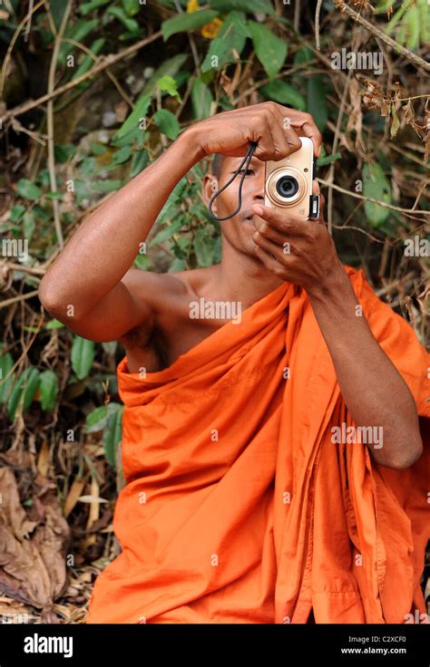 Buddhist monk taking photographs at Bou Sraa Waterfalls. Mondulkiri Province, Eastern Cambodia ...