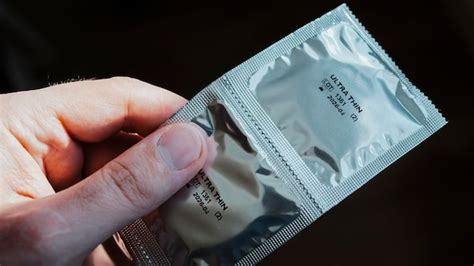 Серебряная упаковка презерватива два ультратонких презерватива в руке ...