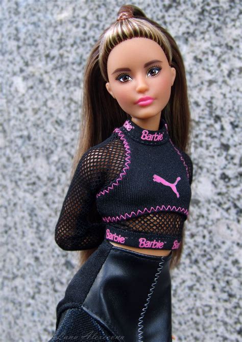 a barbie doll wearing a black outfit with pink letters on the top and ...