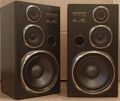 Two Black Speakers Sitting On Top Of A Wooden Floor Next To A Wall