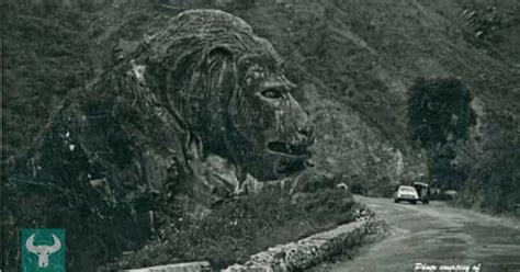 an old black and white photo of a lion head on the side of a road