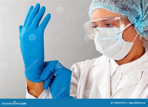 In The Laboratory A Female Scientist Chemist Puts On Protective Gloves