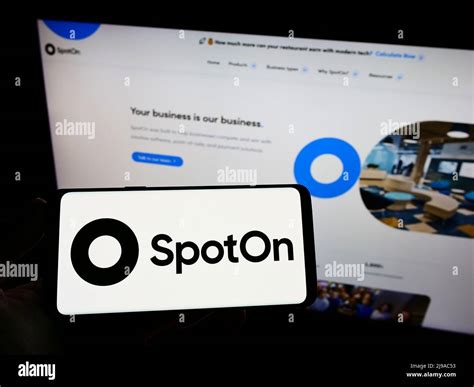 Person Holding Smartphone With Logo Of Us Software Company Spoton