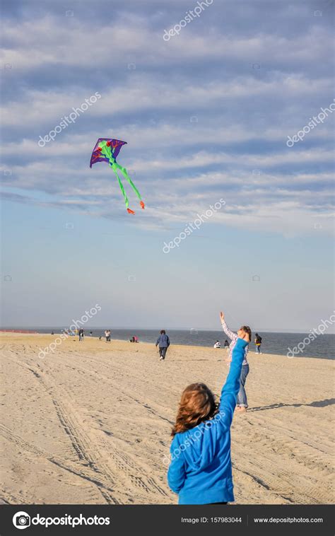 Chica joven volando su cometa en una larga playa de arena fotografía