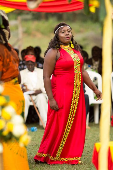 A Woman In A Long Red Dress Standing Next To Other People