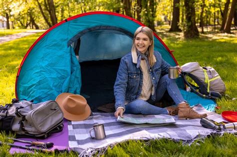 Premium Photo Blonde Cute Female Traveler Sitting Near The Tent In The Forest