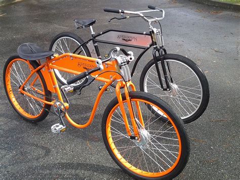 Two Orange Bikes Parked Next To Each Other In A Parking Lot With Trees