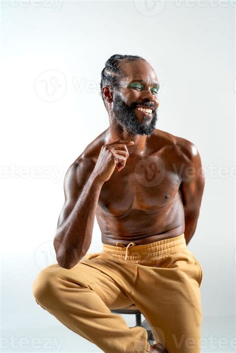 Happy Black Shirtless Gay Model Sitting On Stool In White Studio Stock Photo At Vecteezy