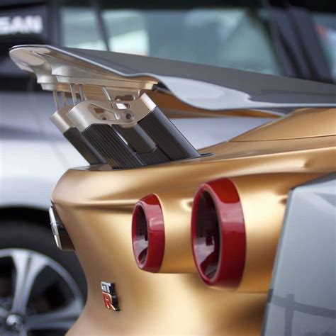 The Rear End Of A Gold Sports Car With Its Hood Up And Two Red Brake Pads