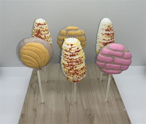 three different colored desserts sitting on top of wooden sticks in front of a white wall