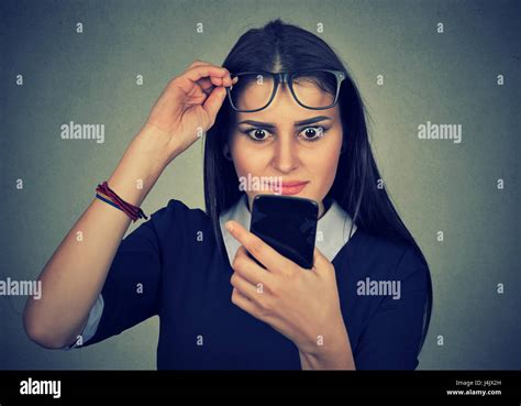 Young Upset Confused Woman With Glasses Looking At Mobile Phone