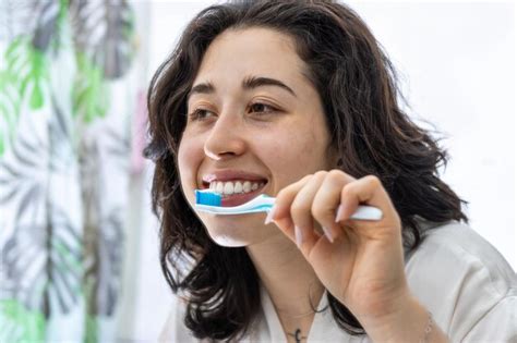 Premium Photo Portrait Of A Beautiful Young Woman Wearing White Towel Brushing Teeth In Front