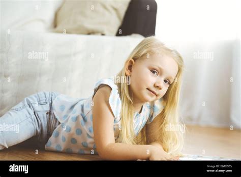 Bonne famille Une jeune mère blonde lit un livre à sa jolie fille tout en étant assise au sol