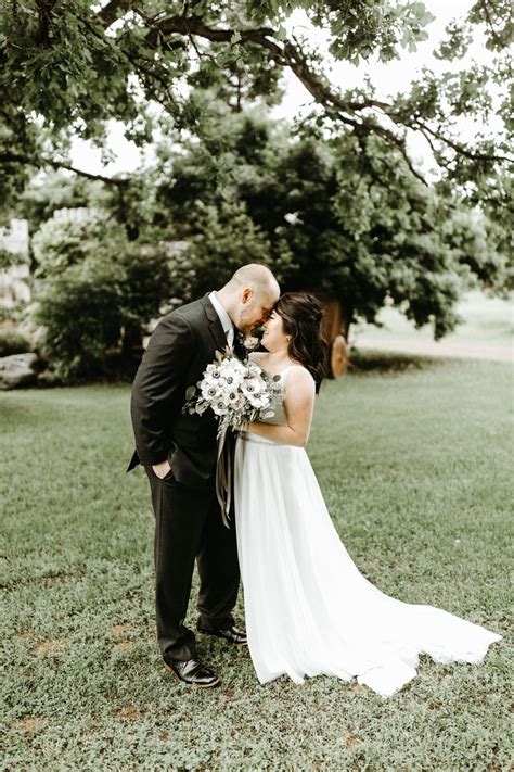 A Bride And Groom Kissing In Front Of A Tree