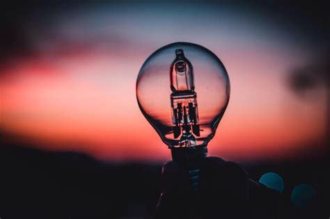 Premium Photo Cropped Hand Of Person Holding Light Bulb Against Sky